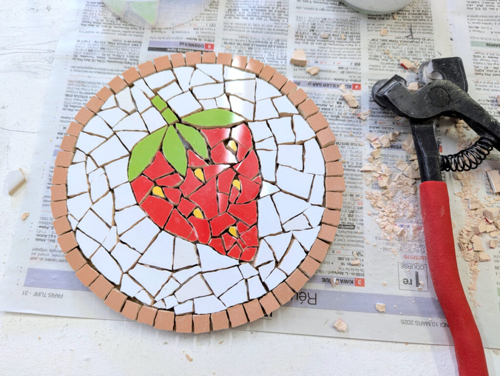 Photo montrant la réalisation faite durant l'atelier de mosaïque: une fraise sur fond blanc
